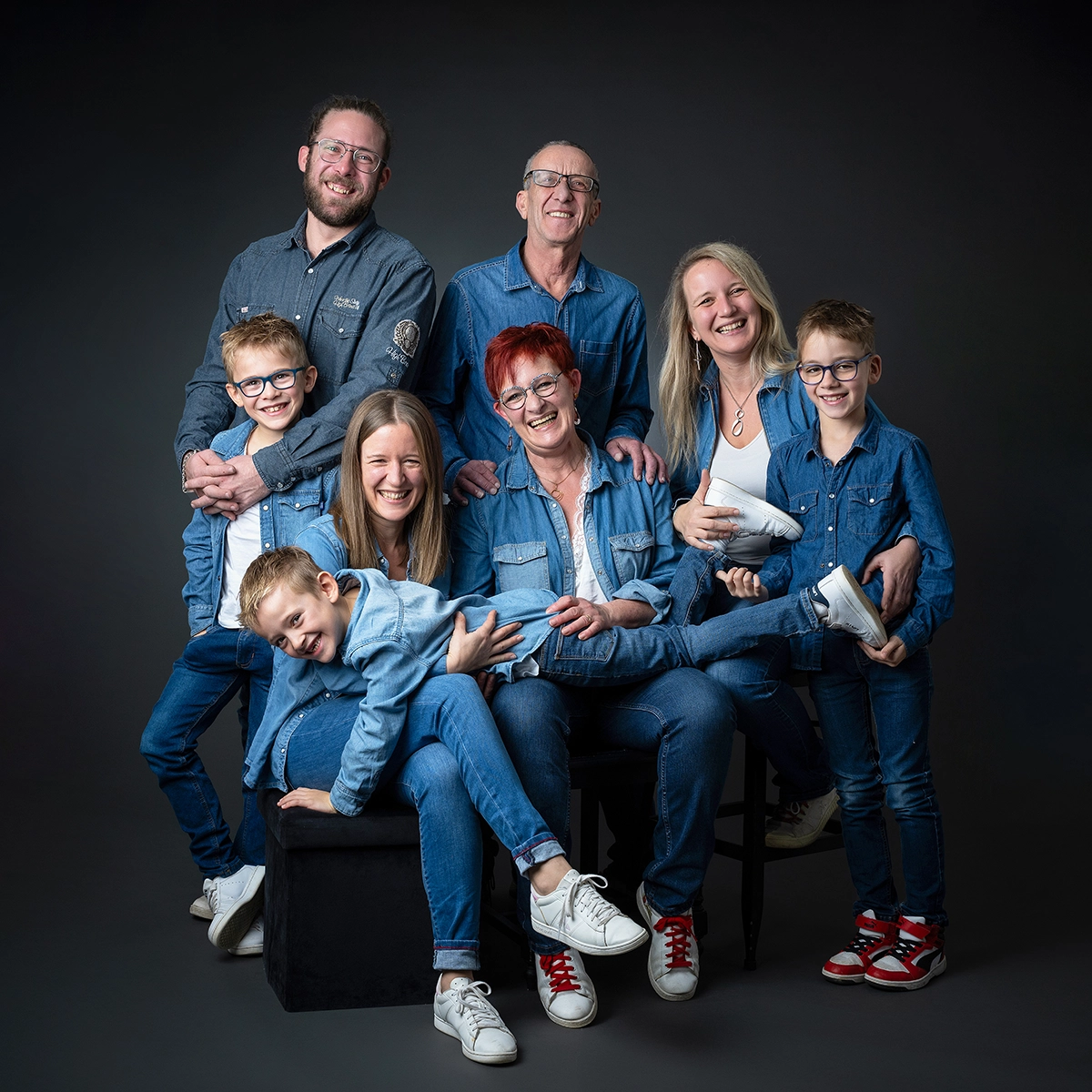 famille de 3 générations papi mamie, enfants et petits enfants en jean bleu sur fond noir