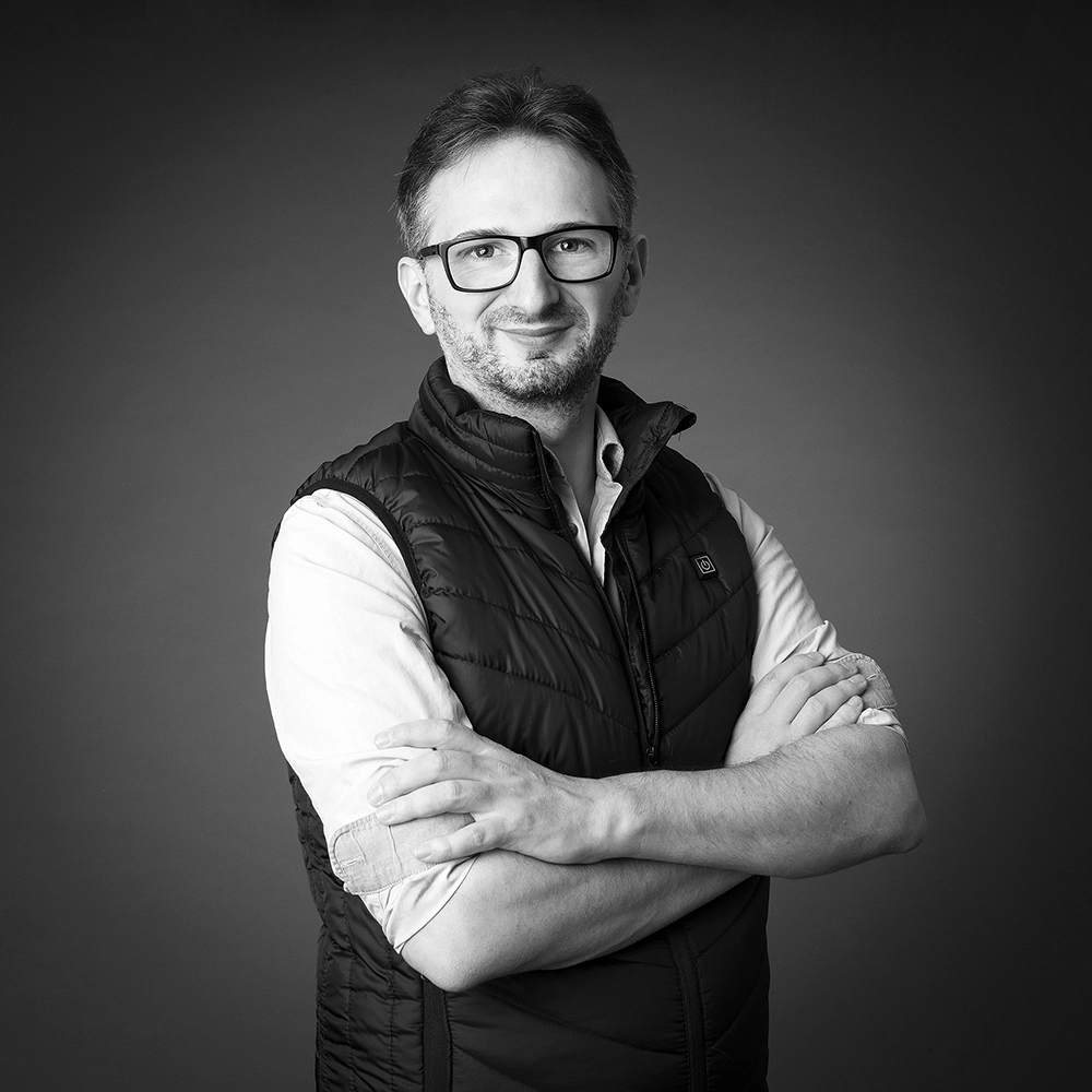 Sophie-mare-Photographe-seingbouse-portrait-corporate-professionel-profil-cv-linkedin-site-internet-06 homme à lunettes sur fond noir, photo noire et blanche, bras croisés avec une veste sans manches