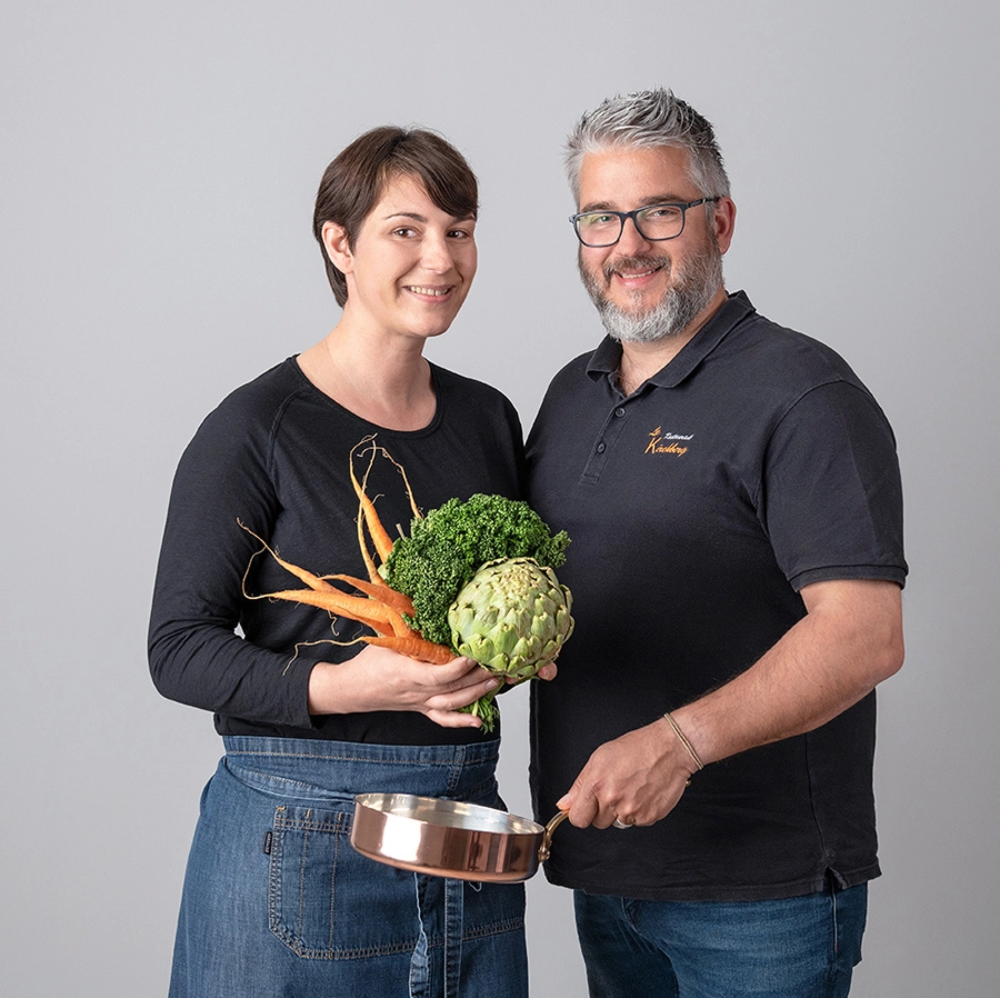 Sophie-mare-Photographe-seingbouse-portrait-corporate-professionel-profil-cv-linkedin-site-internet-21 un couple de restaurateurs en tenue noire, avec une casserole en cuivre et des légumes, sur fond gris