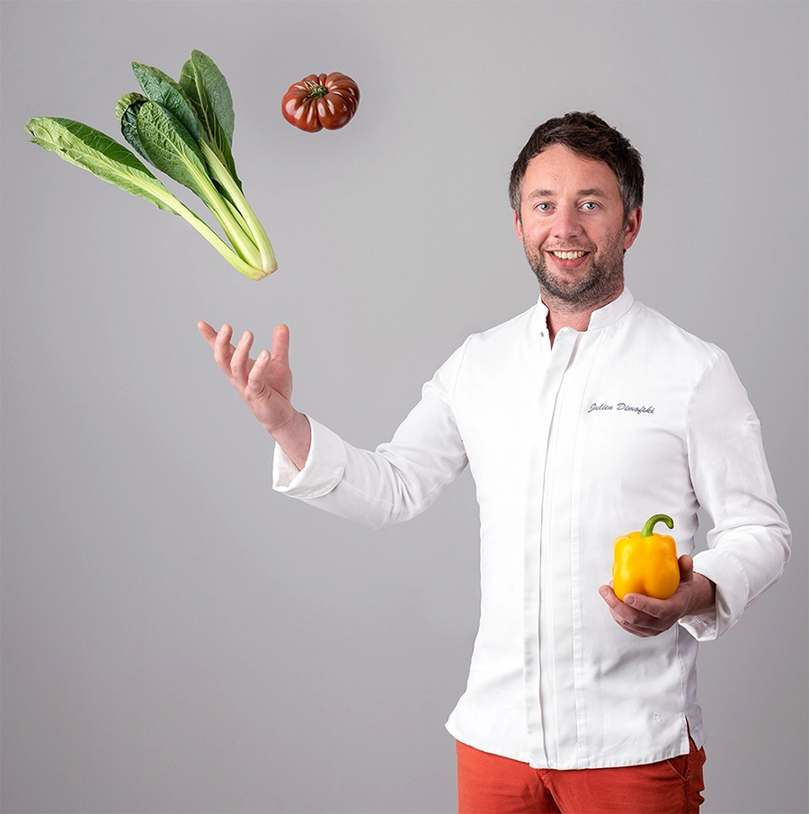 Sophie-mare-Photographe-seingbouse-portrait-corporate-professionel-profil-cv-linkedin-site-internet-34 un restaurateur en tenue blanche sur fond gris, qui jette des légumes en l'air, souriant