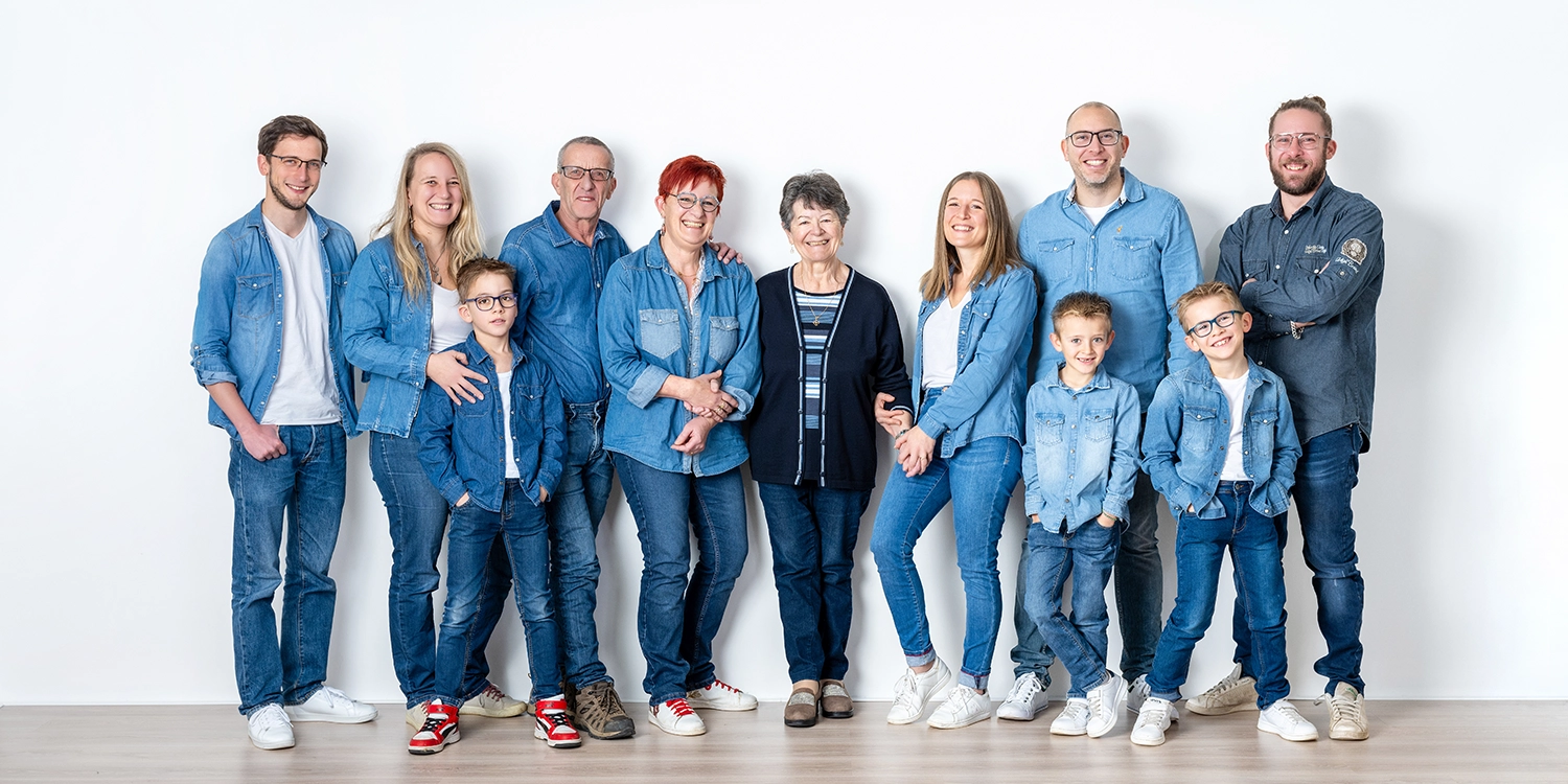 une grande famille photo générationnelle de l'arrière grand-mère, les enfants, les petits enfants et arrière-petits-enfants en jean sur mur blanc