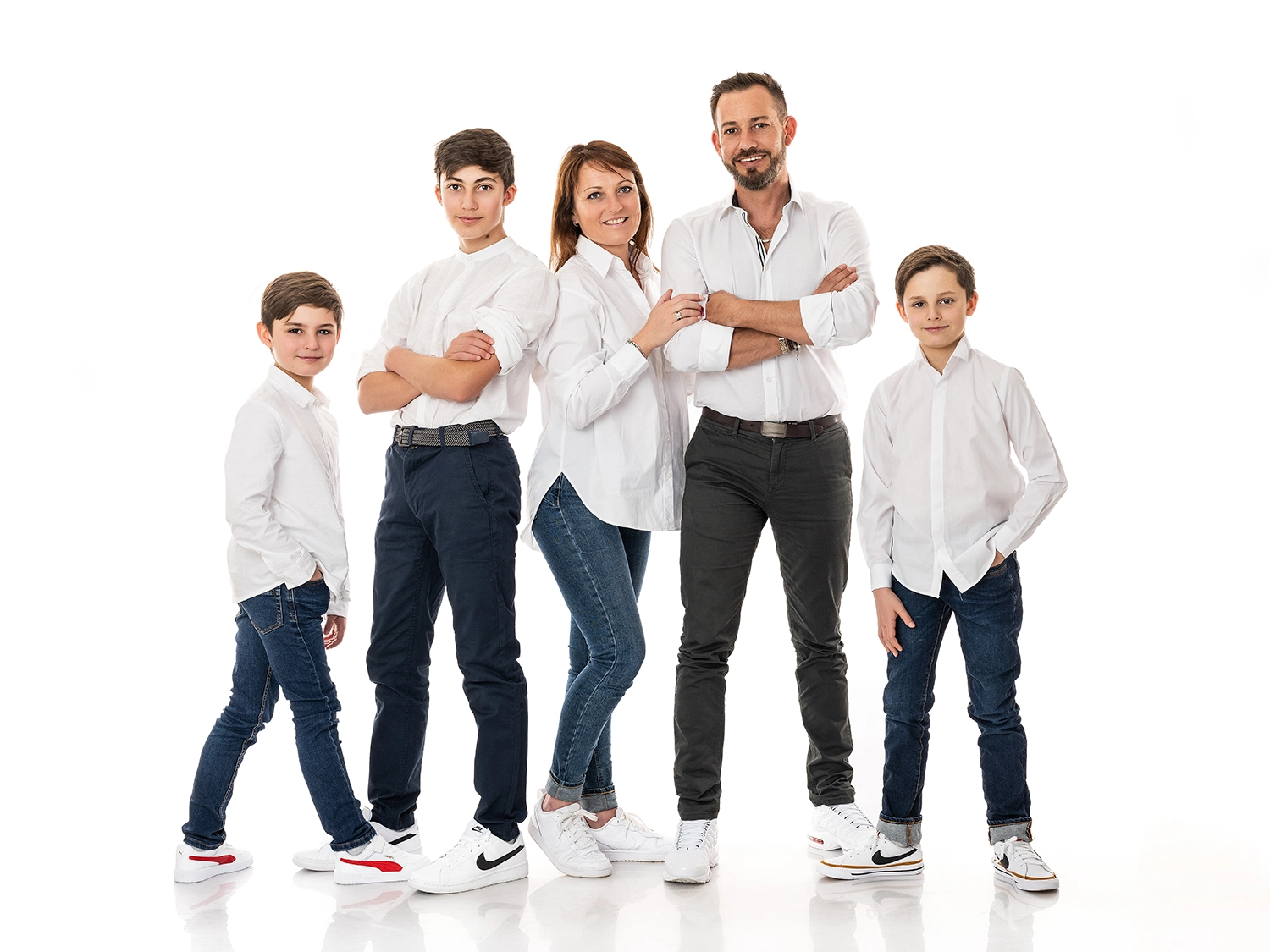 une famille de 5 personnes parents et fratrie de 3 garçon en jean foncé et haut blanc sur fond blanc