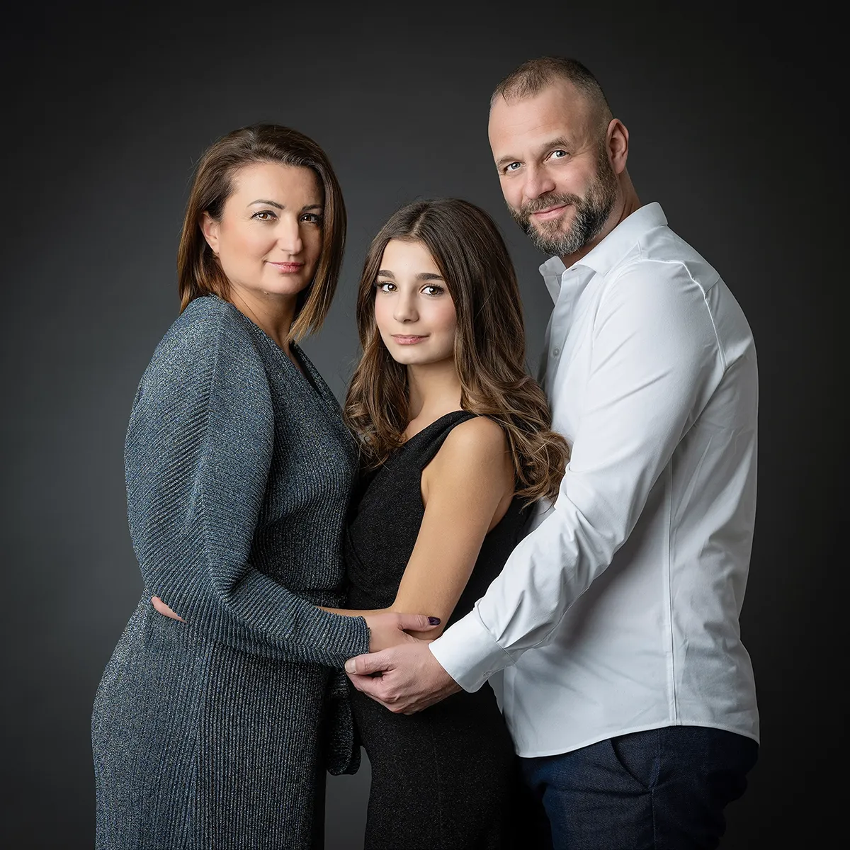 famille de 3 personnes avec une ado et ses parents et tenue élégante sur fond noir