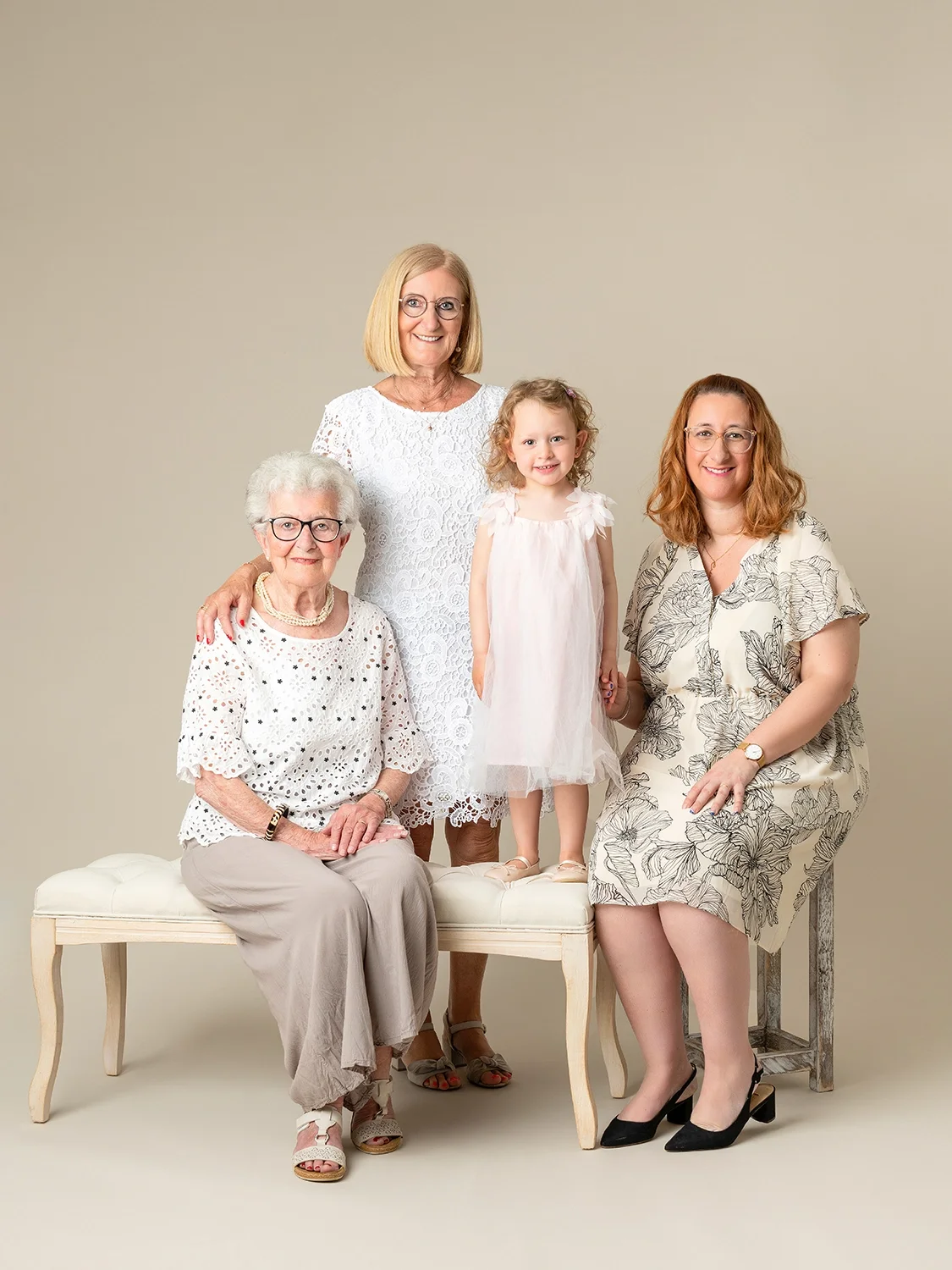 photo générationnelle de 4 générations arrière-grand-mère, grand-mère, mère et fille en robe claire sur fond beige naturel
