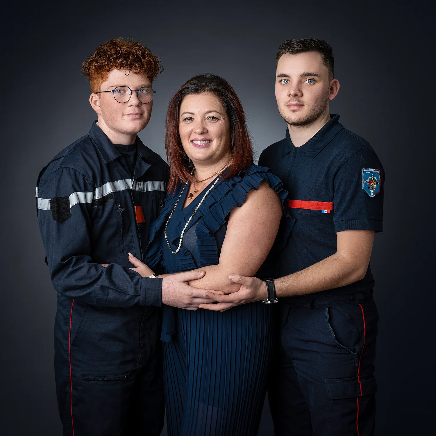 maman et ses 2 fils. un garçon roux. maman en robe bleue marine et les 2 garçon en pompiers.