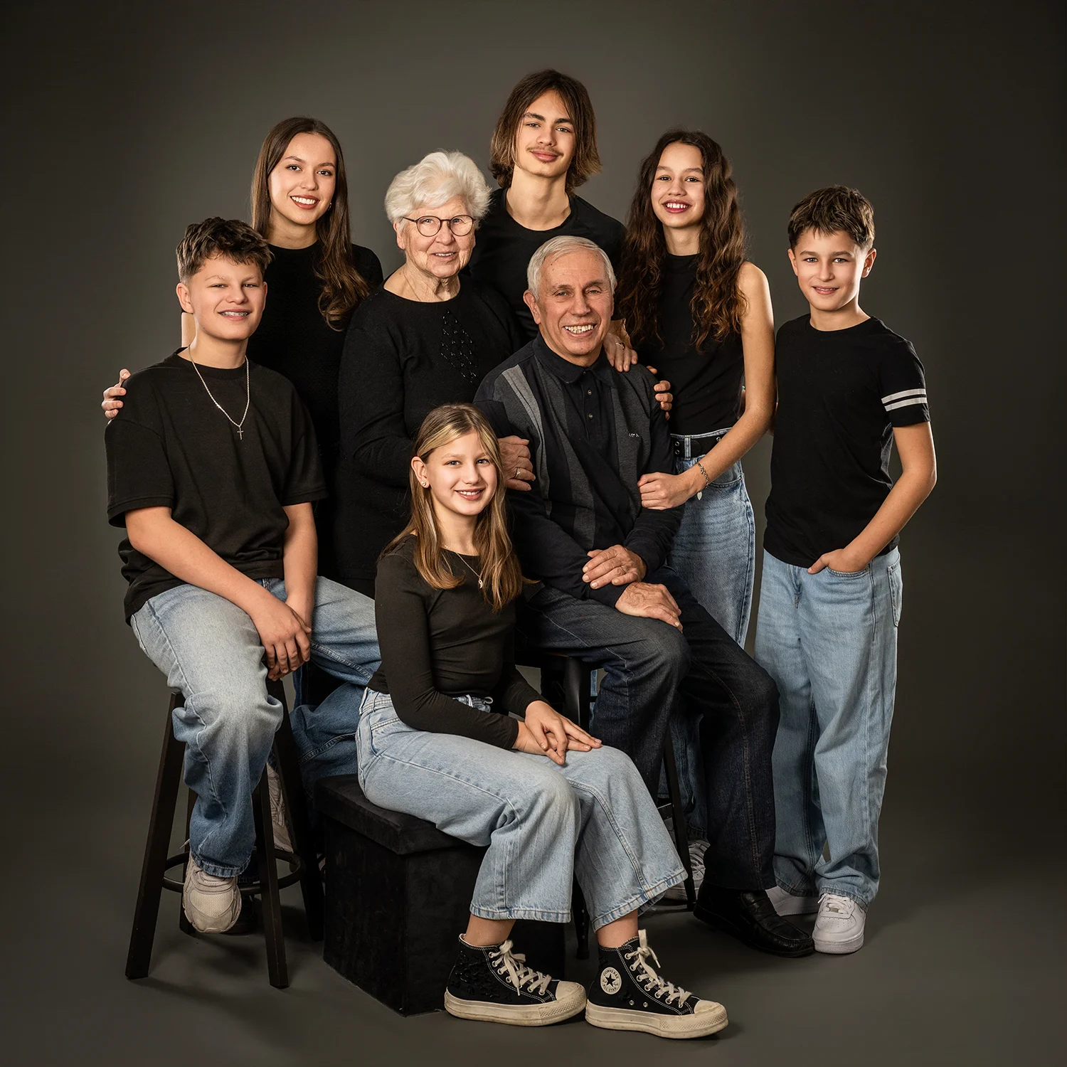 grands-parents et fratrie et cousins en t-shirt noir et jean sur fond noir
