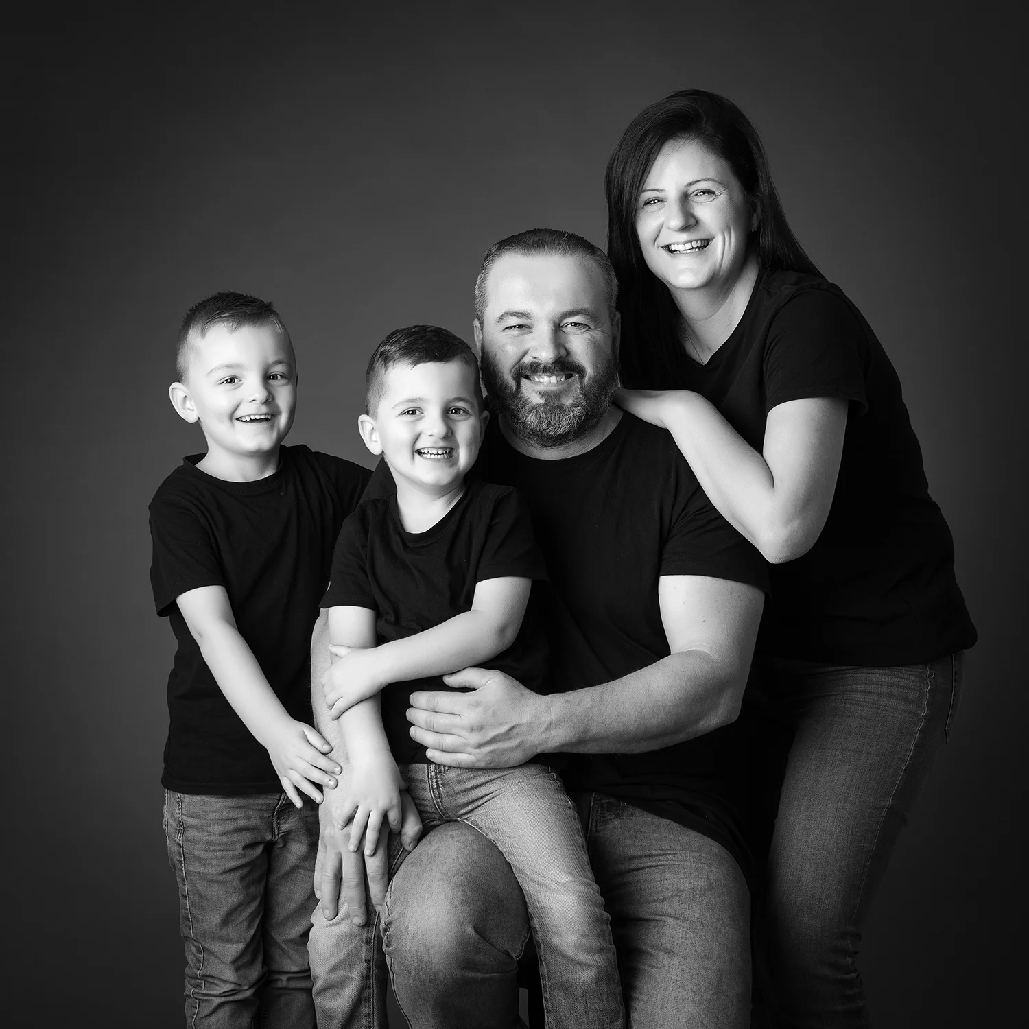 famille de parents et 2 petits garçons en t-shirt noir sur fond noir