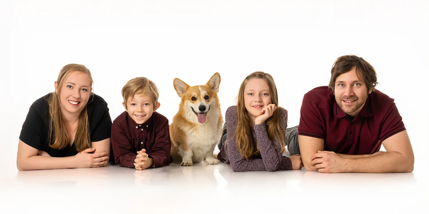 une famille parents enfants et un chien corgi au milieu au sol sur fond blanc