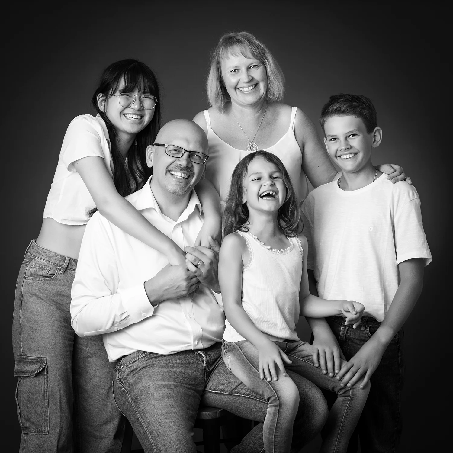 une famille de 5 personnes ado asiatique, fou rire, en noir et blanc sur fond noir