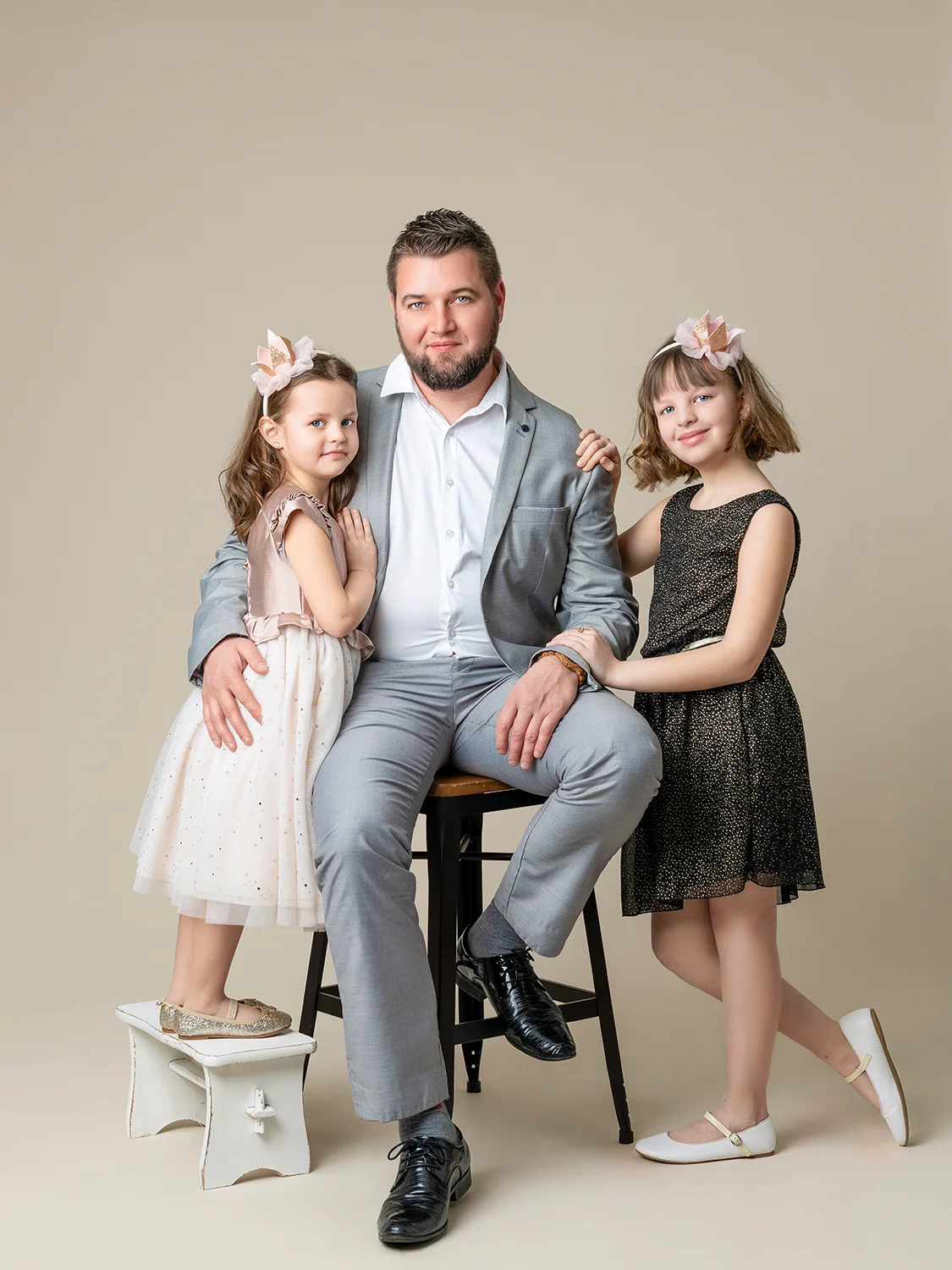 papa en costume, petites filles en tenues élégantes sur fond blanc naturel