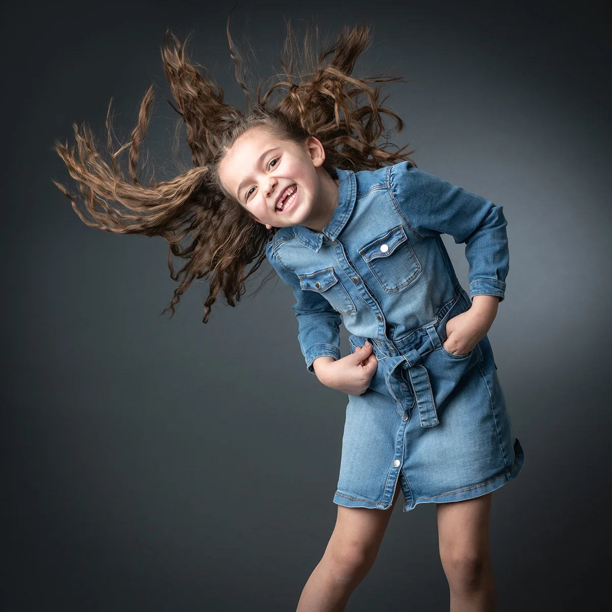 studio-seingbouse-photographe-sophie-julien-mare-fratrie-enfant-parents-frere-soeur-portrait-01 petite fille cheveux bouclés qui fait voler ses cheveux, robe en jean sur fond gris