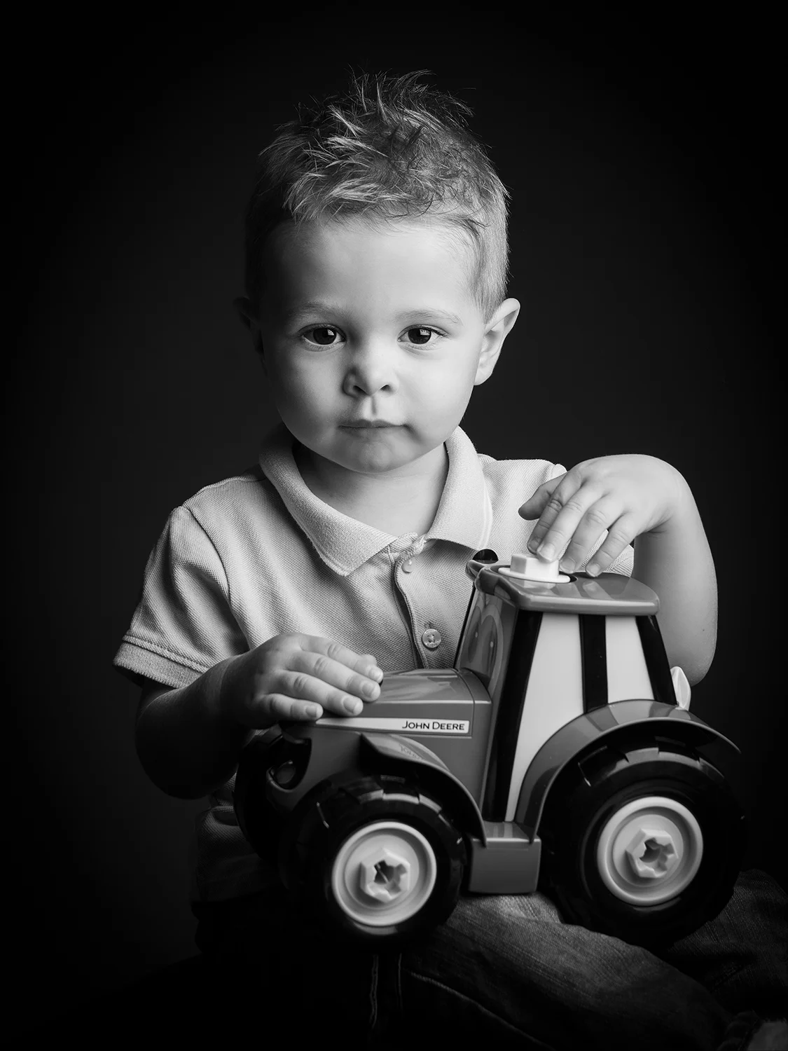 studio-seingbouse-photographe-sophie-julien-mare-fratrie-enfant-parents-frere-soeur-portrait-09 petit garçon qui tient un tracteur, sur fond noir