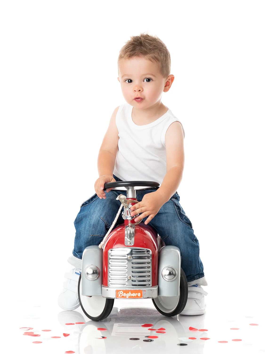 studio-seingbouse-photographe-sophie-julien-mare-fratrie-enfant-parents-frere-soeur-portrait-10 petite garçon sur un camion de pompiers, fond blanc et confettis rouges, en débardeur et jean et fond blanc