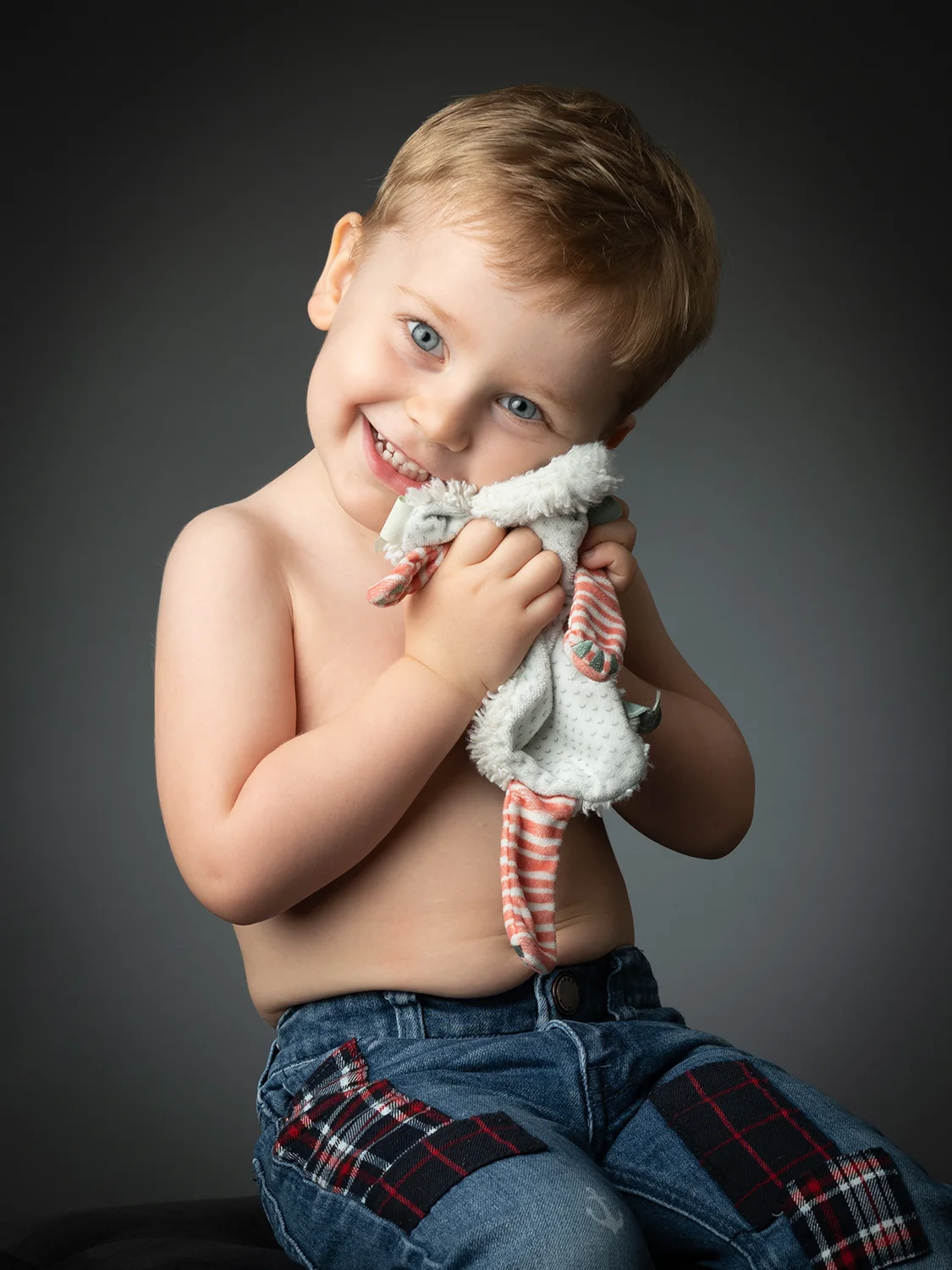 studio-seingbouse-photographe-sophie-julien-mare-fratrie-enfant-parents-frere-soeur-portrait-13 petit garçon torse nu qui fait un câlin à son doudou sur fond gris