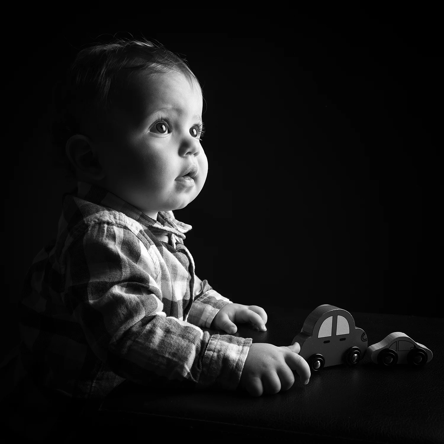studio-seingbouse-photographe-sophie-julien-mare-fratrie-enfant-parents-frere-soeur-portrait-14 bébé, regard penseur, avec des jouets en bois et une chemise à carreaux sur fond noir