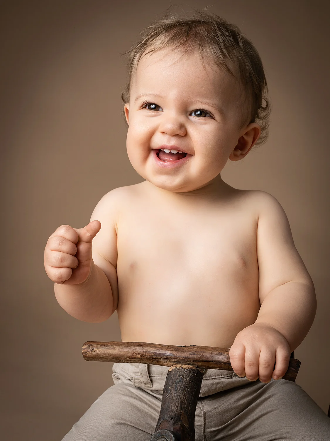studio-seingbouse-photographe-sophie-julien-mare-fratrie-enfant-parents-frere-soeur-portrait-15 garçon avec le pouce levé, 1 an, qui sourit, sur un vélo en bois