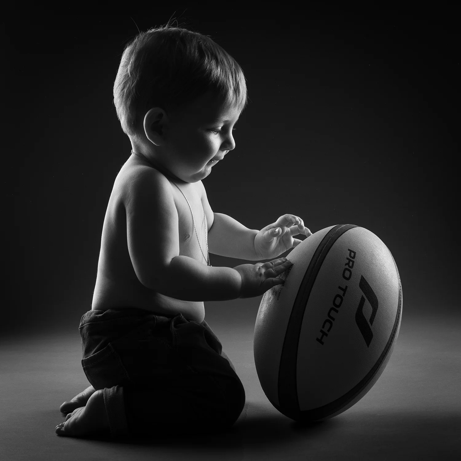 studio-seingbouse-photographe-sophie-julien-mare-fratrie-enfant-parents-frere-soeur-portrait-17 petit garçon de profil avec un ballon de rugby sur fond noir