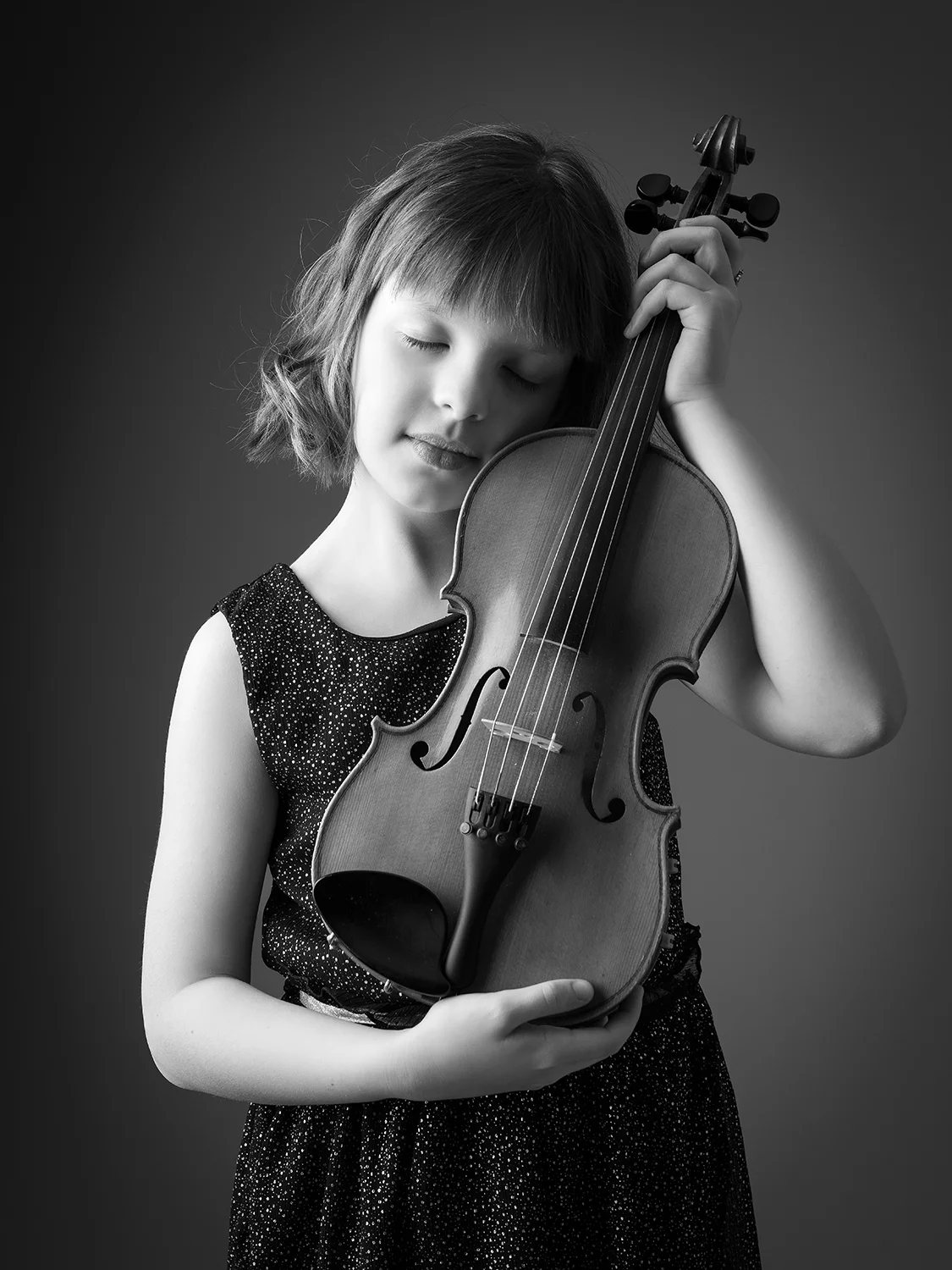 studio-seingbouse-photographe-sophie-julien-mare-fratrie-enfant-parents-frere-soeur-portrait-32 petite fille en robe, yeux fermés, visage contre son violon, fond gris