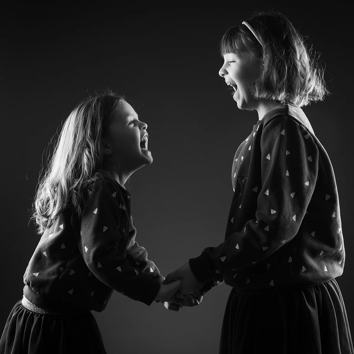 studio-seingbouse-photographe-sophie-julien-mare-fratrie-enfant-parents-frere-soeur-portrait-33 2 soeurs qui se regardent, de profil, fond noir et qui éclatent de rire