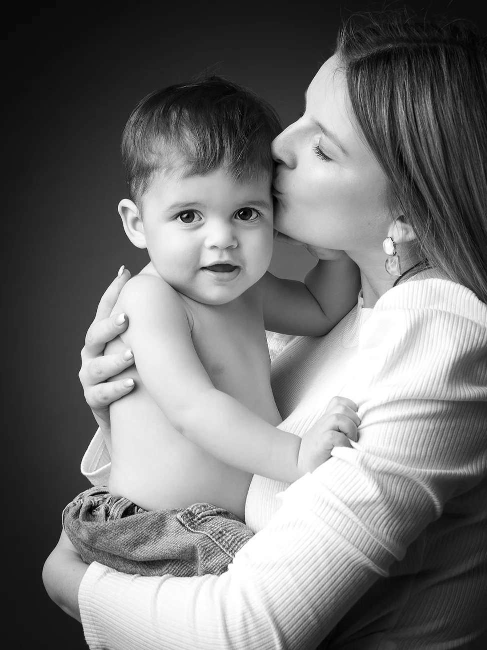 studio-seingbouse-photographe-sophie-julien-mare-fratrie-enfant-parents-frere-soeur-portrait-35 petit garçon torse nu, sa maman lui fait un bisou, sur fond noir