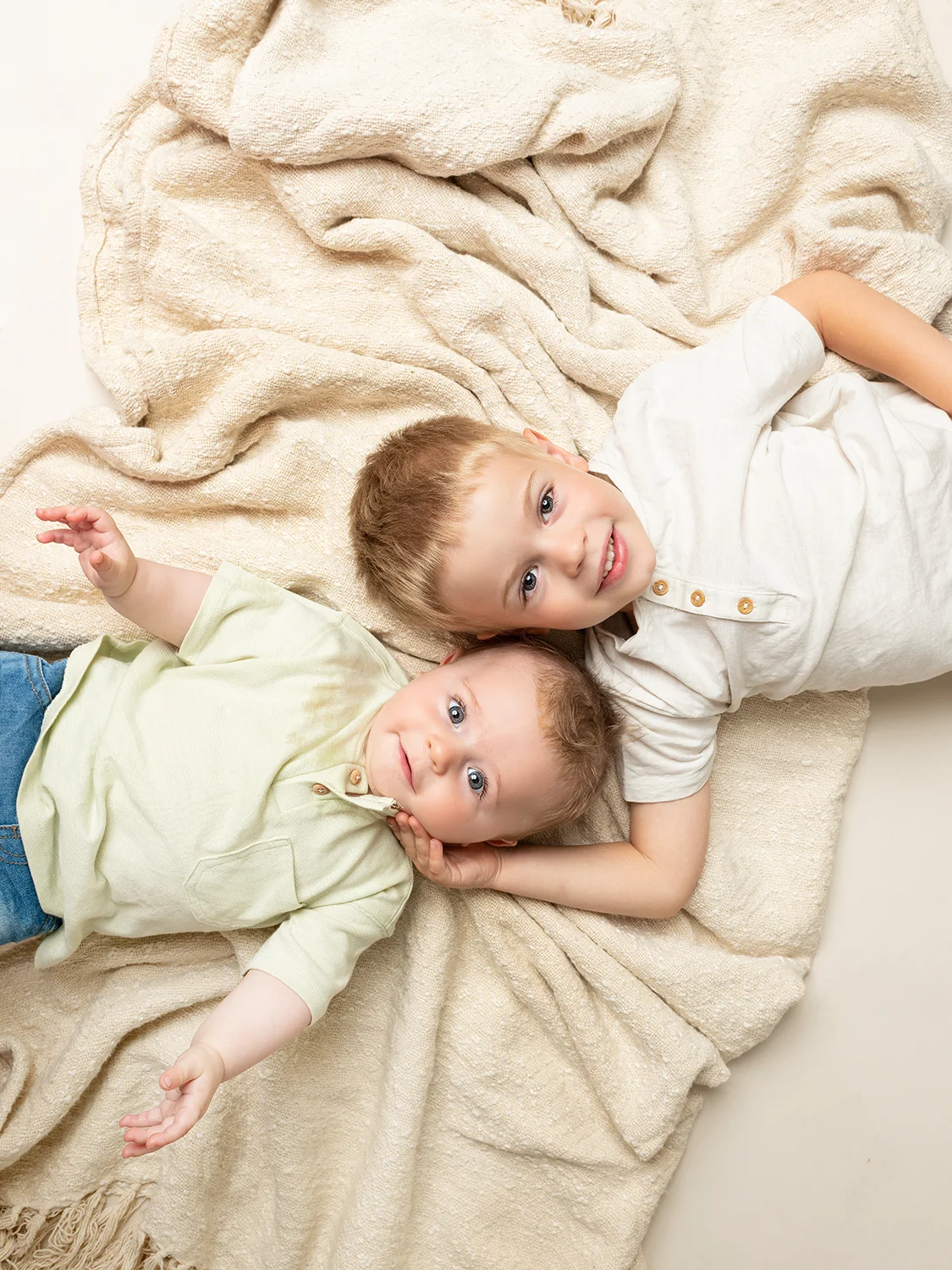 studio-seingbouse-photographe-sophie-julien-mare-fratrie-enfant-parents-frere-soeur-portrait-61 frères couchés sur le dos, vue de dessus, avec un tissu beige
