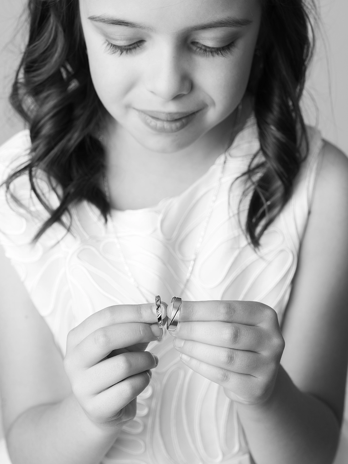 studio-sophie-mare-mariage-photos-seingbouse-merlebach-portrait-03 une petite fille en robe blanch qui tient en main les alliances de ses parents et qui les regardent