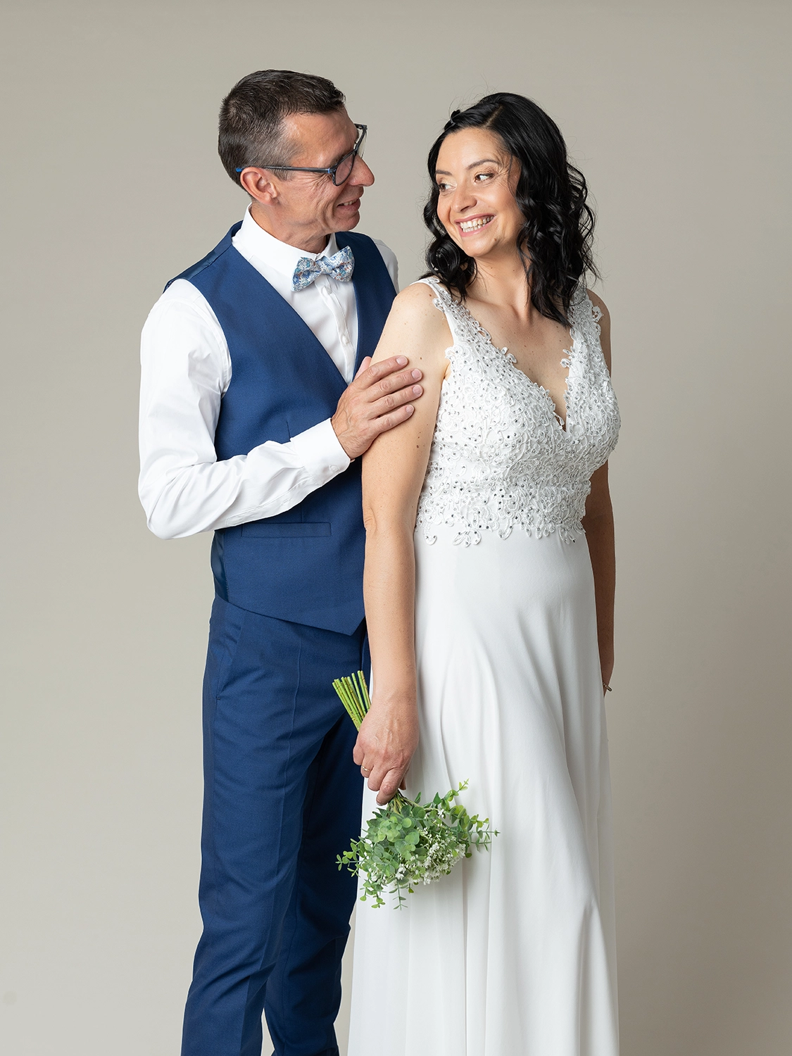 studio-sophie-mare-mariage-photos-seingbouse-merlebach-portrait-07 un couple de mariés sur fond beige naturel qui se regarde. La mariée a un bouquet en main