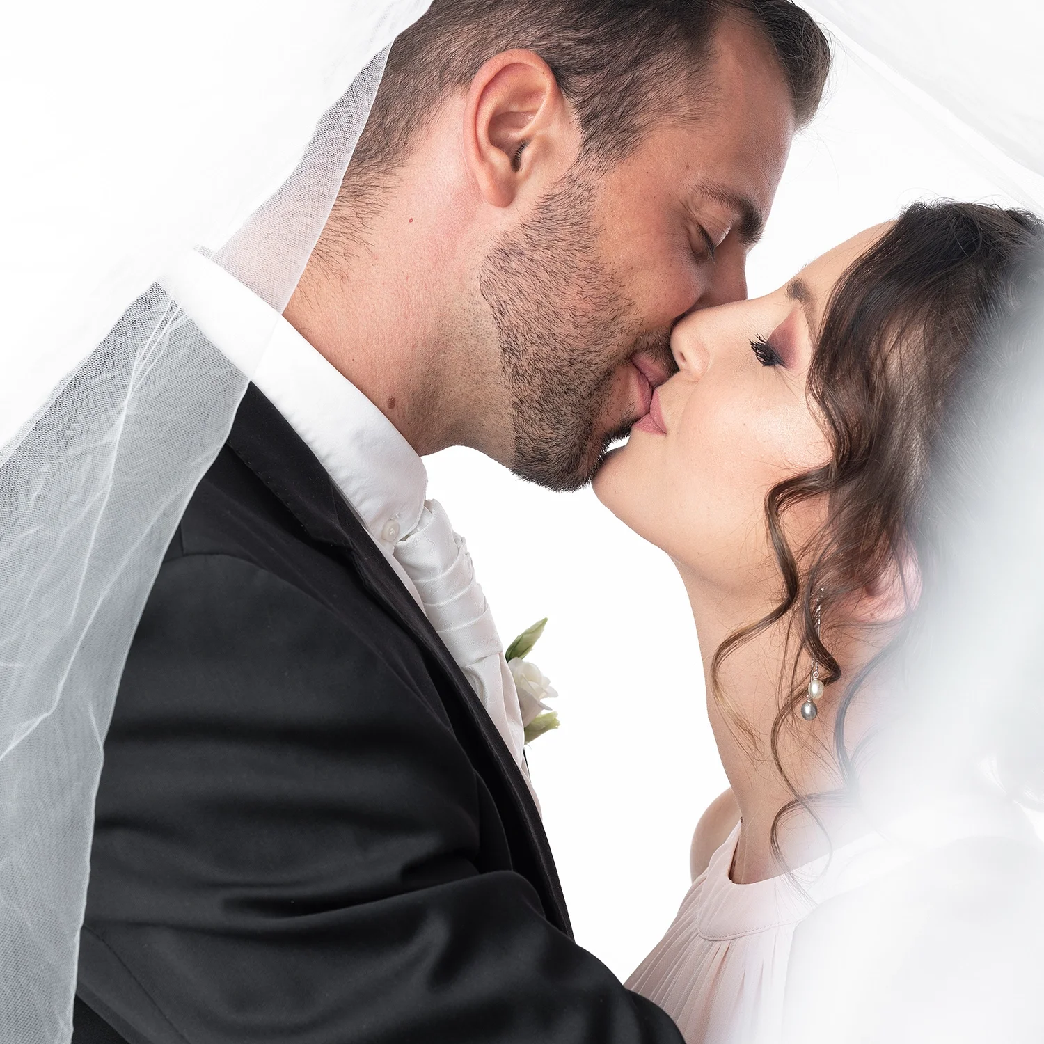 studio-sophie-mare-mariage-photos-seingbouse-merlebach-portrait-11 un couple de mariés sous un voile, qui s'embrasse. Le marié est en costume