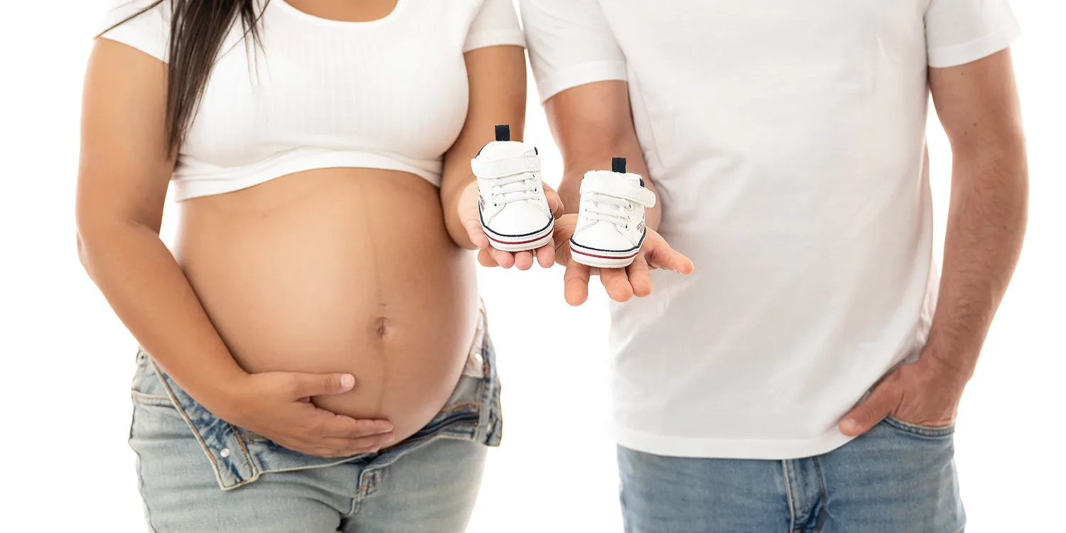 studio-seingbouse-photographe-sophie-julien-mare-grossesse-enceinte-parents-bebe-naissance-shooting-06 un papa et une future maman enceinte, qui tiennent sur leur main une paire de chaussures de bébé