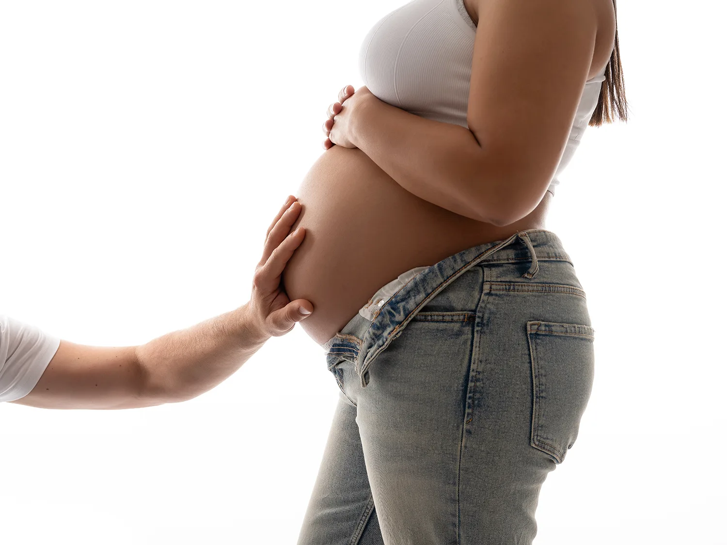 studio-seingbouse-photographe-sophie-julien-mare-grossesse-enceinte-parents-bebe-naissance-shooting-09 un ventre de femme enceinte en jeann avec la main de papa posée dessus