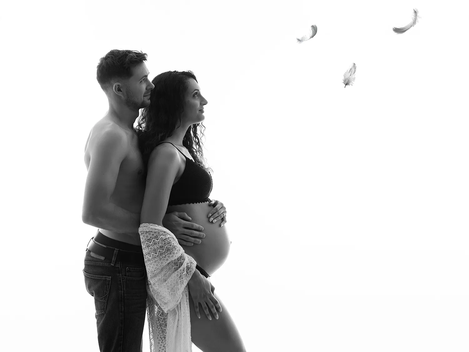 studio-seingbouse-photographe-sophie-julien-mare-grossesse-enceinte-parents-bebe-naissance-shooting-16 un couple de profil, qui regarde des plumes qui volent, la femme est enceinte